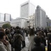 People stand outside after evacuating buildings in Tokyo's financial district in Tokyo after an earthquake off the coast of northern Japan