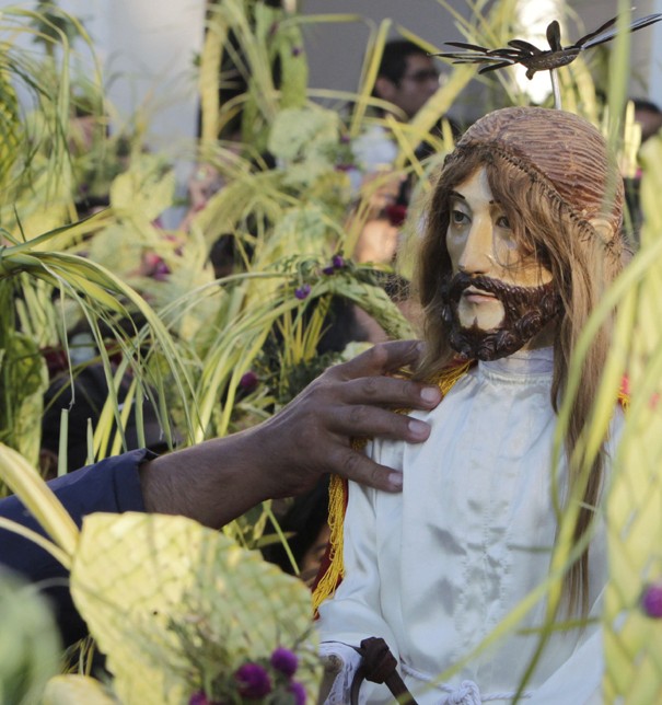 Catholics surround a statue of Christ as they take part in a procession while celebrating Palm Sunday outside the Metropolitan Cathedral in Capiata